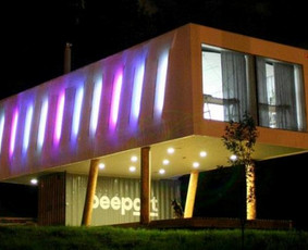 Neįprastas pastatas Pilaitėje: juriniai konteineriai, apšiltinti šiaudais, apželdintas stogas. RGB LED fasado apšvietimas po tentu. Atrodo kosmiškai.